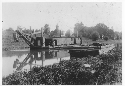 William J. McKelvey noted in his 1975 book that silting from rain and floods was a constant concern on the Delaware and Raritan Canal, and that periodic dredging was required during the years the canal was in operation.  This photograph shows a dredge boat on the Feeder Canal north of the Church Road swing bridge in the Titusville community of Hopewell Township.